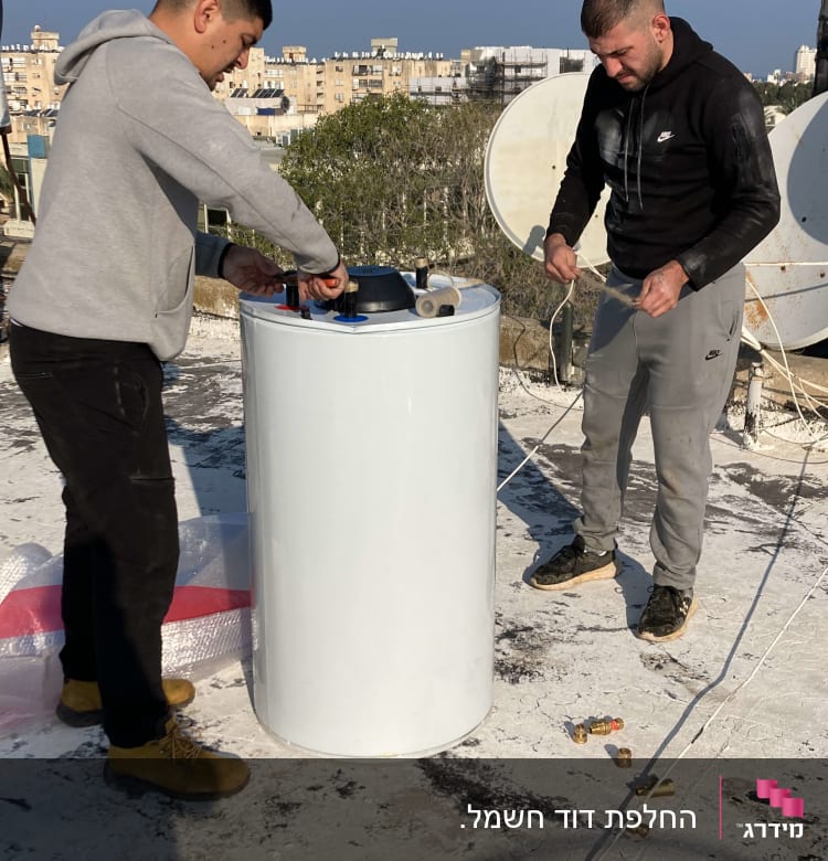 שני אנשים מתקינים דוד שמש על גג